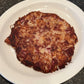 Plated dish with hash browns, poached eggs, toast, and condiments on a white plate.